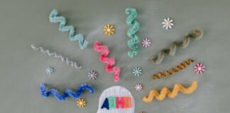 Stock photo of a person's side profile with the letters "ADHD" over its head. There are curled pipe cleaners in various colors surrounding the person's head as well as small plastic flowers.