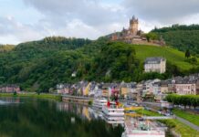 Photo of a castle on a hill above the water. Lots of small houses are below the hill on the waterfront.