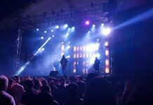5 Fun Events in November: African Diaspora Gala, Fashion Show, Live Rock Bands Stock photo of a crowd of people at a rock concert. There are blue strobe lights lighting up the dark room.