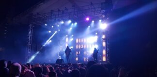 Stock photo of a crowd of people at a rock concert. There are blue strobe lights lighting up the dark room.
