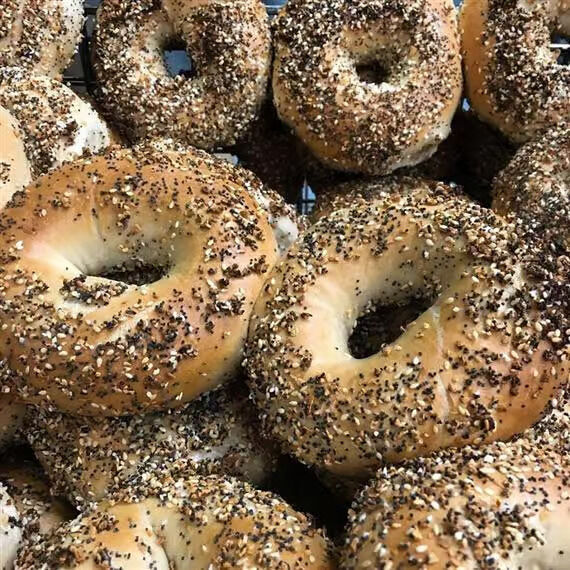 Close-up of a bunch of everything bagels, topped with sesame seeds, poppy seeds and onion flakes.