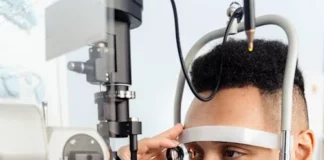 Stock photo of a man at the eye doctor getting his eyes examined by an apparatus.