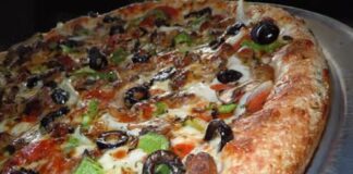 Close-up of a pizza topped with green peppers and black olives.