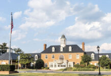 Photo of the exterior of a historic-looking brick bank building. There are two tall flagpoles outside.
