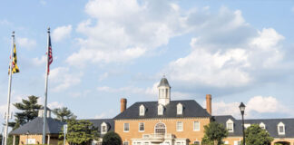 Photo of the exterior of a historic-looking brick bank building. There are two tall flagpoles outside.