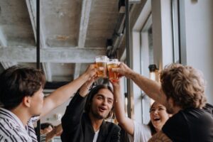 Stock photo of four young adults making a toast, each with a glass of beer in hand.