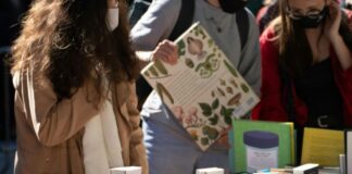 Stock photo of a few people browsing a table covered with stacks of books.