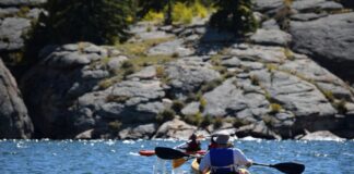 Stock photo of people kayaking in a river surrounded by rocks.