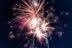 Stock photo of red and white fireworks against a dark night sky.