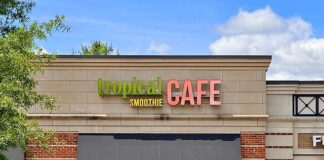 Photo of the exterior of a cafe building with a small black awning. The sign reads "Tropical Smoothie Cafe."