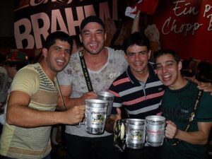 Stock photo of four young middle-aged men holding steins of beer and smiling.