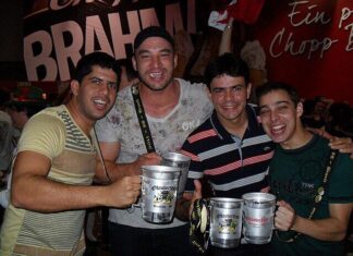 Stock photo of four young middle-aged men holding steins of beer and smiling.