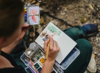 Stock photo of a person painting with watercolor in the woods.