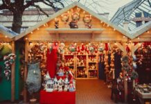 14 Holiday Markets Coming Up in MoCo Photo of a holiday market in a wooden house-like structure with shelves of plush animals, ornaments and Christmas-themed decor.