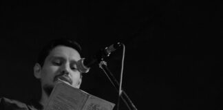 Man reading poetry from a book at an open mic